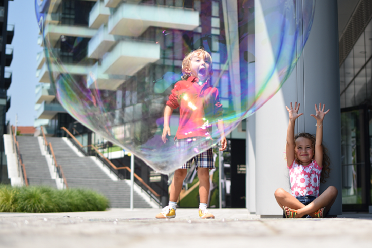 Children playing behind a large bubble