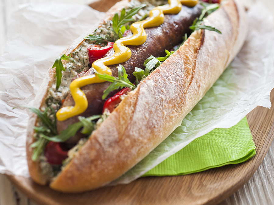 Chorizo hot dog with roasted red capsicum, salsa verde mayonnaise & rocket