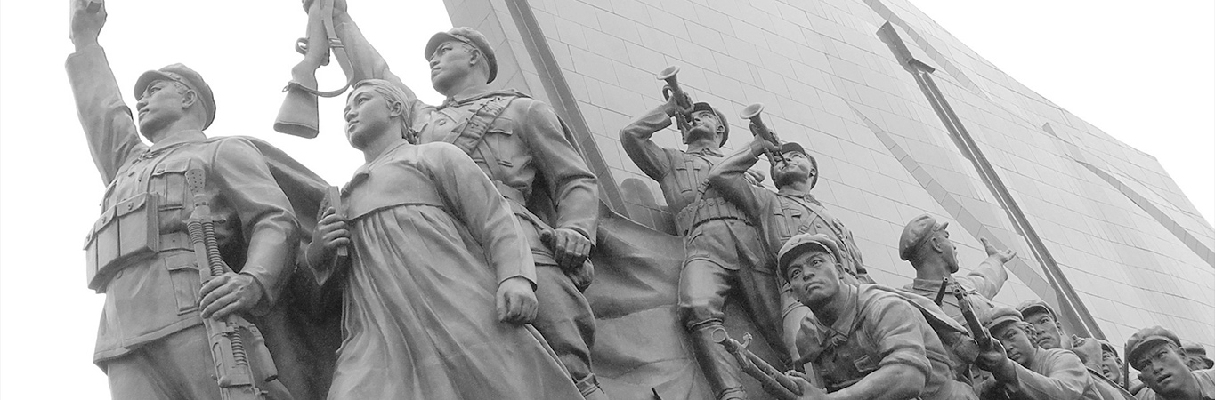 Communist style sculpture of soldiers and workers against a background of stark architecture