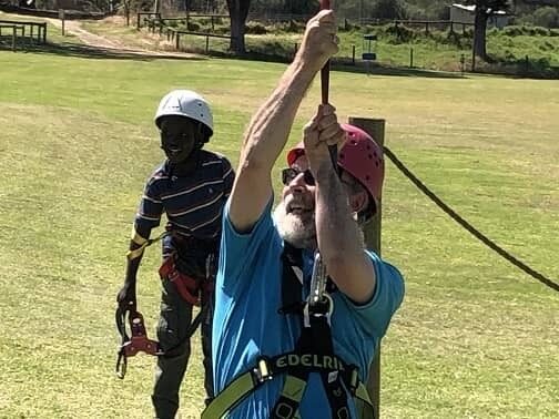 Bishop Jeremy James on flying fox with child looking on