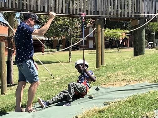 Child and adult playing on flying fox