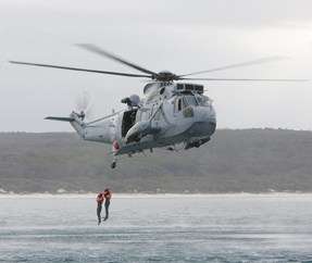 Sea King Helicopter mid air lowering an officer to the water