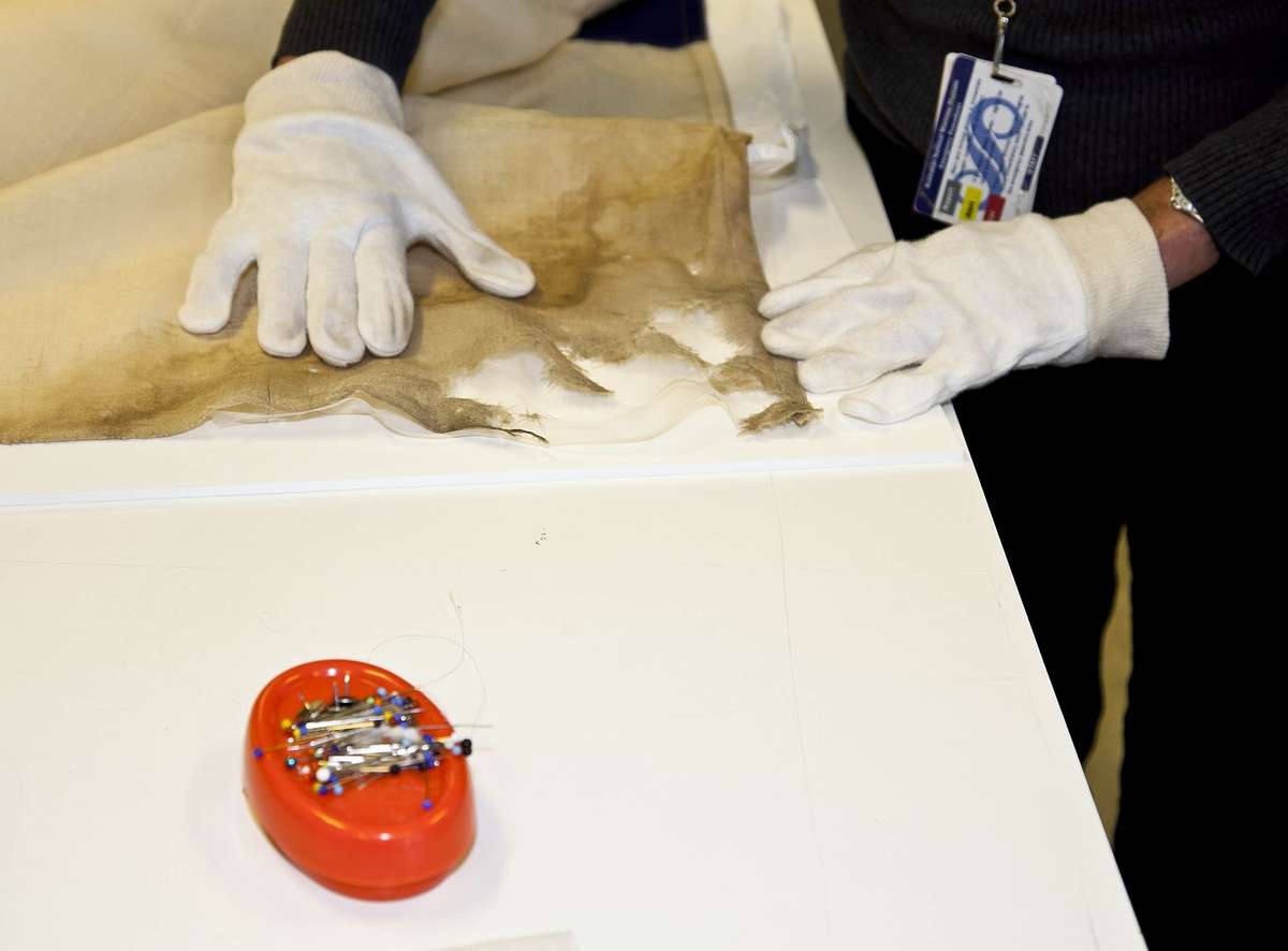 The conservator stabilises areas of fabric loss.