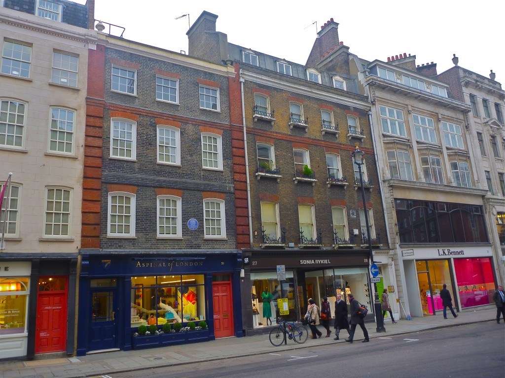 Photo of street with old apartments with shops at ground level.