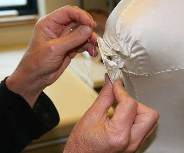 Sue sewing edge of mannequin arm