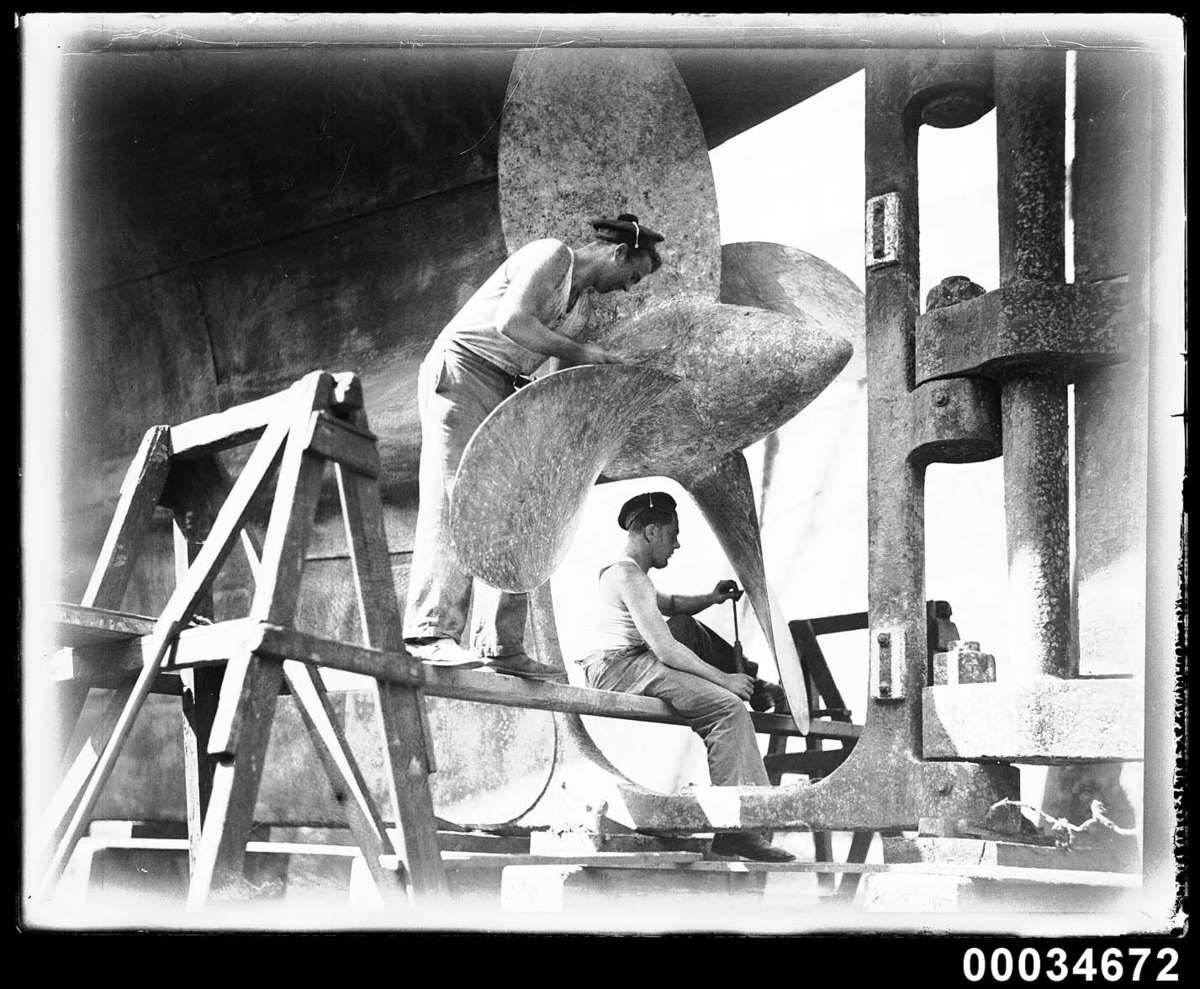 Two sailors cleaning a propeller of the French warship Bellatrix, 1930-1932 Photographer: Samuel J Hood Studio ANMM Collection