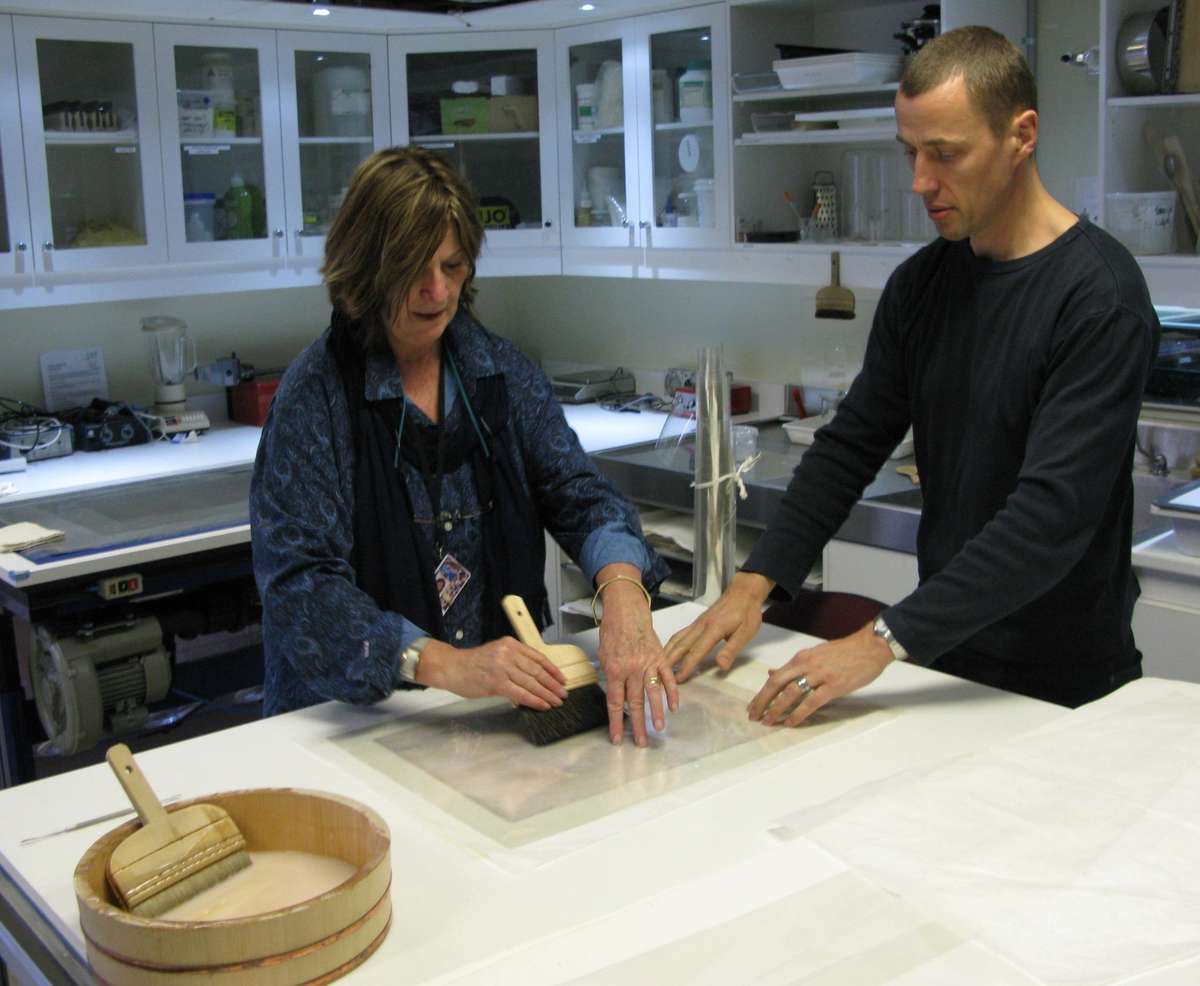 Senior Paper Conservator Caroline Whitley and Head of Conservation Jonathan London line a fragile watercolour with Japanese repair tissue.