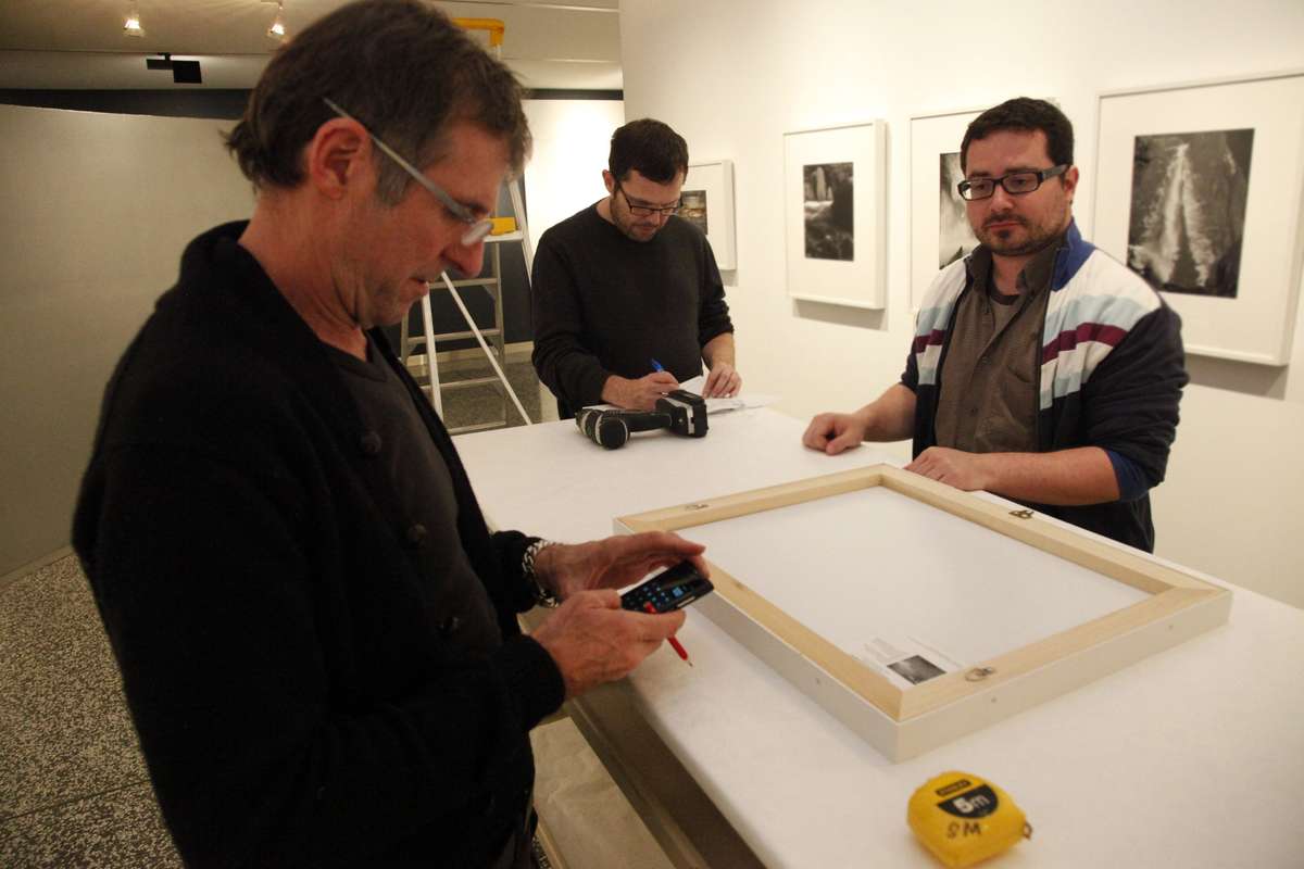 Three museum staff members installing photographs