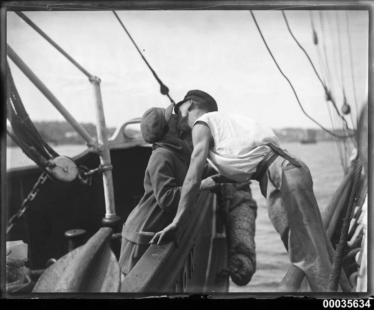 Man and woman kissing across two vessels