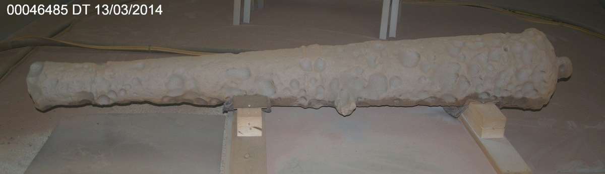 Bare metal on one side of the cannon exposed during garnet blasting.