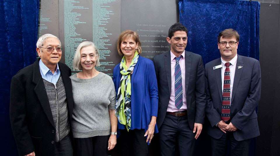 Guest speakers stand in front of the Welcome Wall