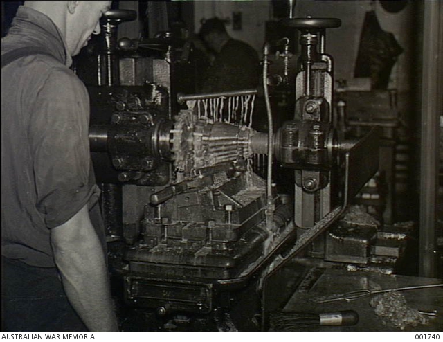 A munitions employee watches a milling machine at the Small Arms ...