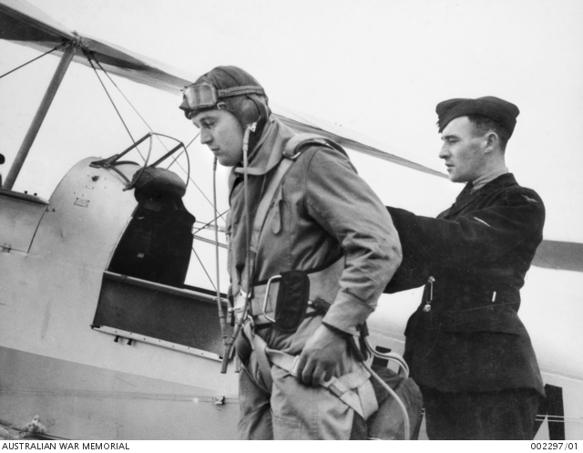 A RAAF TRAINEE HAS HIS PARACHUTE ADJUSTED BY A LEADING AIRCRAFTMAN ...