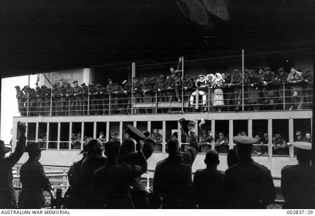 A group of Army personnel on the wharf wave farewell to those lining ...