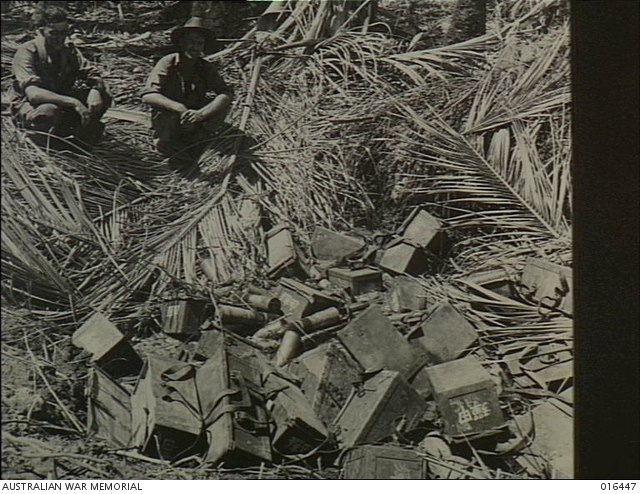 New Guinea. Two soldiers looking over full cases of ammunition and 75mm ...
