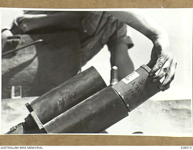 SINGLETON, NSW. 1943-01. PLACING THE SMOKE CANISTER INTO THE BARREL OF ...