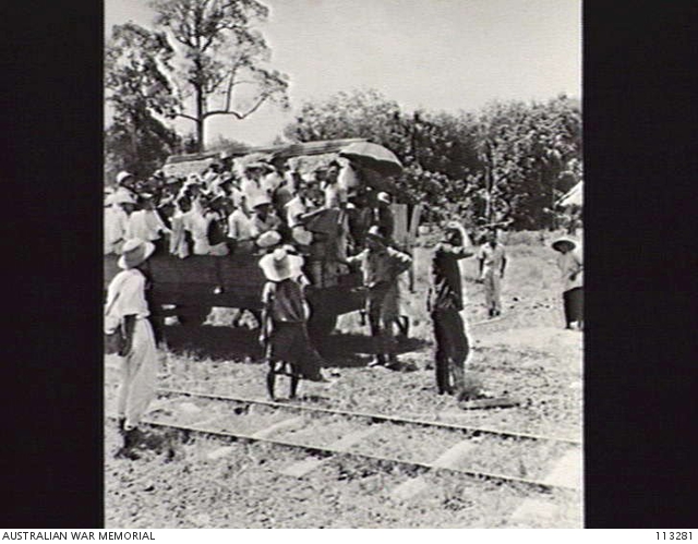 MEMBAKUT, BORNEO, 1945-08-09. A JEEP TRAIN LOAD OF NATIVES AT THE LOCAL ...