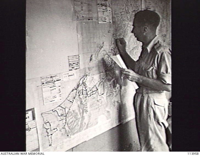 MOROTAI. 1945-08-25. SERGEANT A. D. BUDGE MARKING THE POSITIONS OF ...