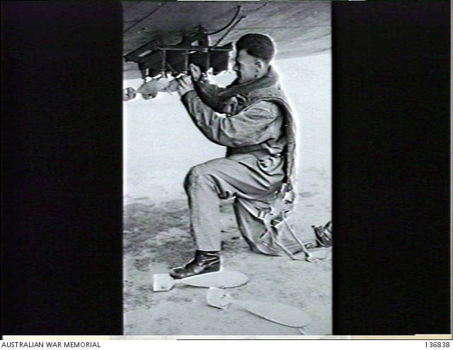 SALE, VIC. 1942-09-23. A RAAF OBSERVER FITTING 8 POUND PRACTICE BOMBS ...