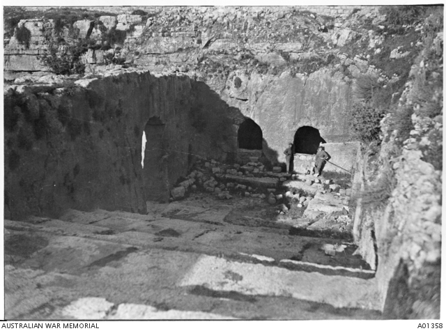 Two German soldiers standing with a dog between them in the ruins of a ...