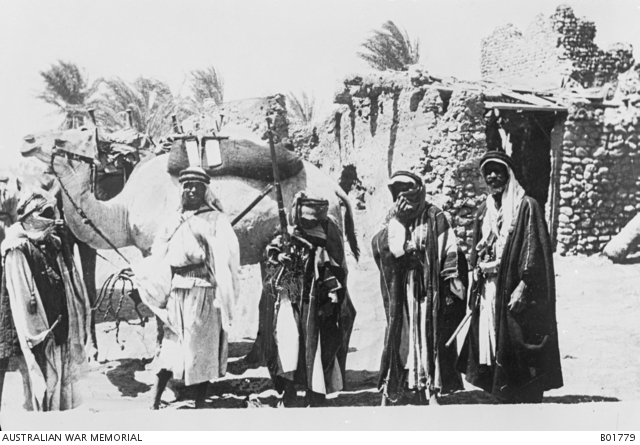 Arab soldiers standing with a camel. In the background to the right a ...