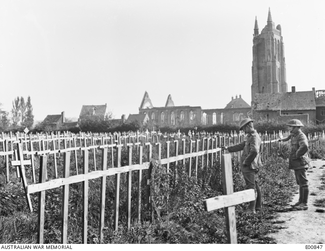 Two unidentified soldiers look at the inscriptions on the crosses at ...
