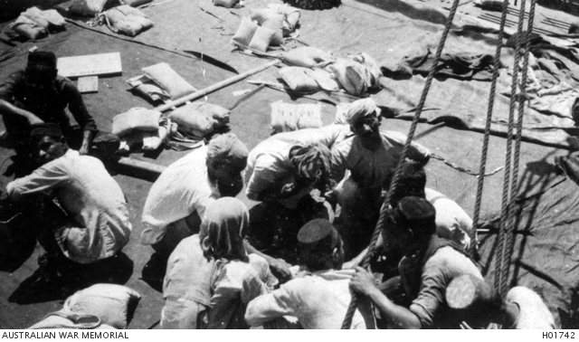 AT SEA. 1919. NATIVE MEMBERS OF THE CREW OF HMAT TAKADA CONSUMING A MEAL ON  THE DECK. | Australian War Memorial