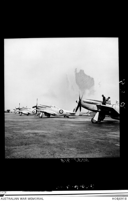 Two unidentified RAAF personnel (right) stand on the wings of a Mustang ...