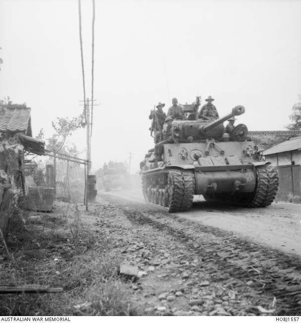 Troops of 3rd Battalion, The Royal Australian Regiment (3RAR), mounted on US M4A3E8 tanks, take