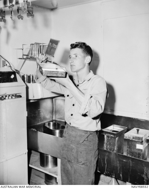 RAN photographer R59691 Geoffrey Thomas ‘Fish’ Herring examines a ...