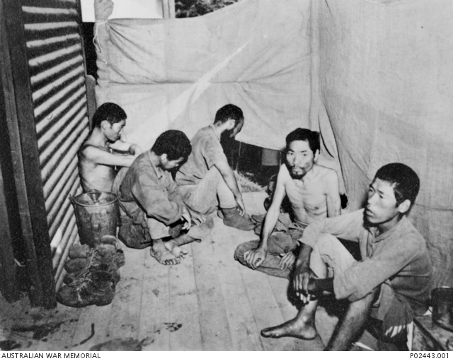 A group of five Japanese prisoners of war (POWs) sit on the floor of a ...