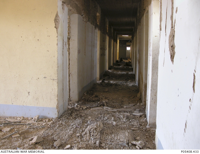 Debris and rubble lines the corridor, off which are numerous cells, at ...