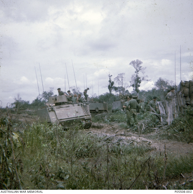 Soldiers survey a damaged armoured personnel carrier (APC) which drove ...