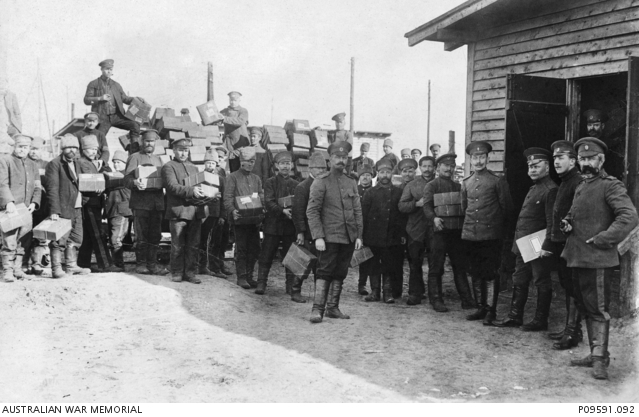 A large group of prisoners of war (POW) unloading parcels from a cart ...