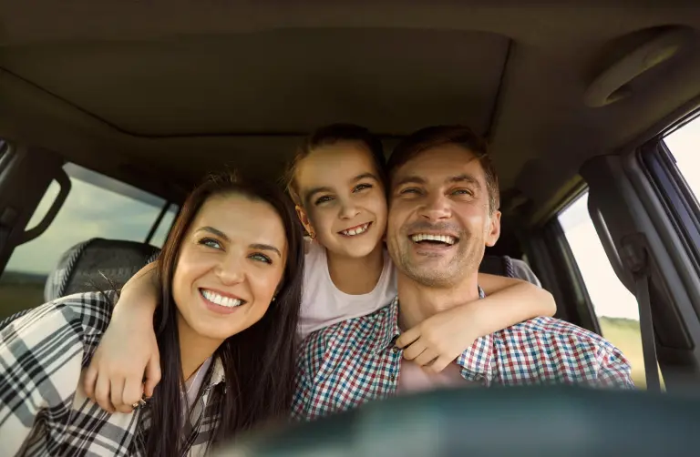 Happy family smiling together inside a car during a road trip
