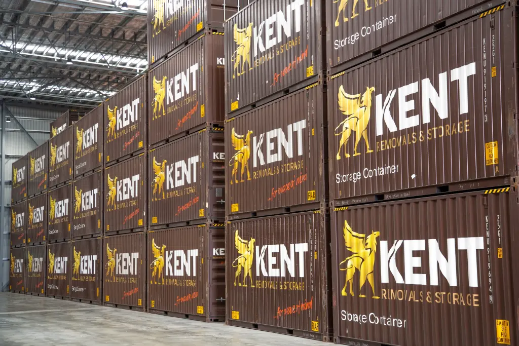 Stacked Kent Removals & Storage shipping containers inside a warehouse storage facility