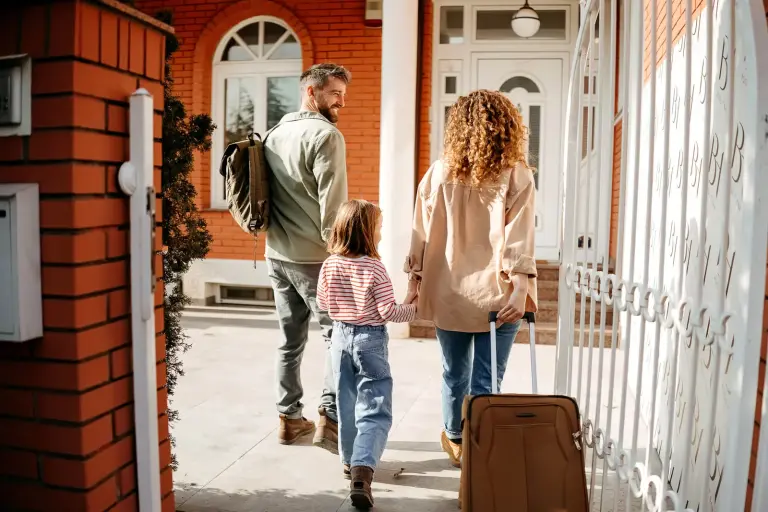 Family arriving at new home with luggage during relocation process