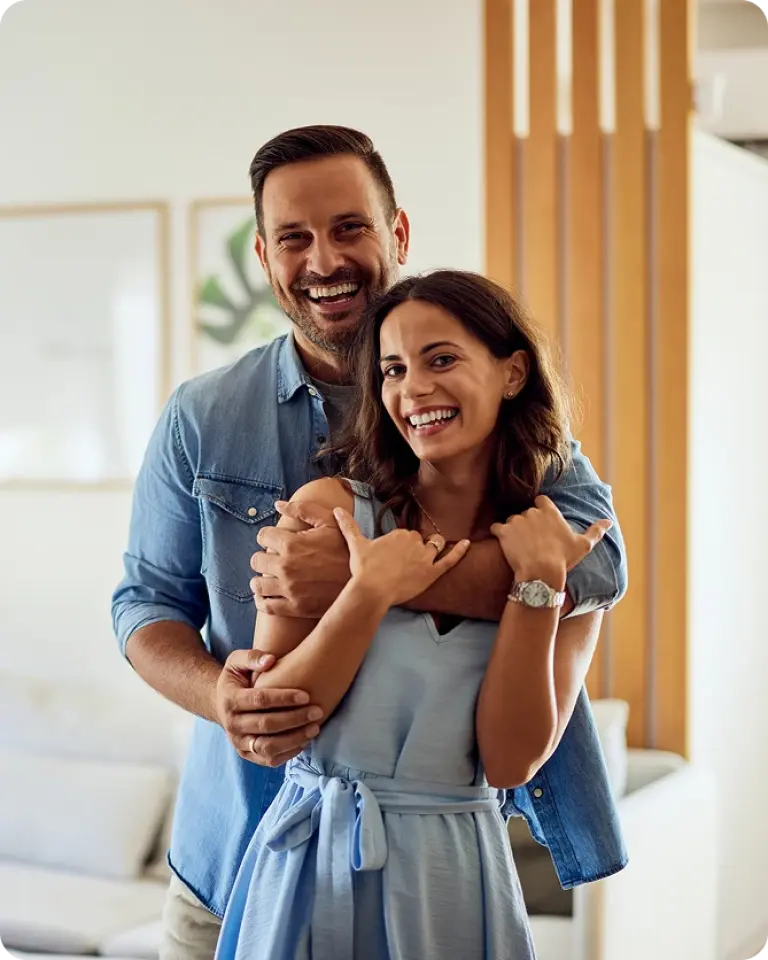 Happy couple standing together inside new home after moving in