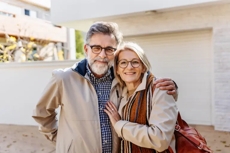Senior couple standing outside their home after moving in