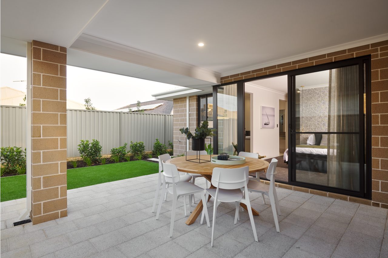 Covered outdoor dining area connected to the home by expansive sliding glass doors.