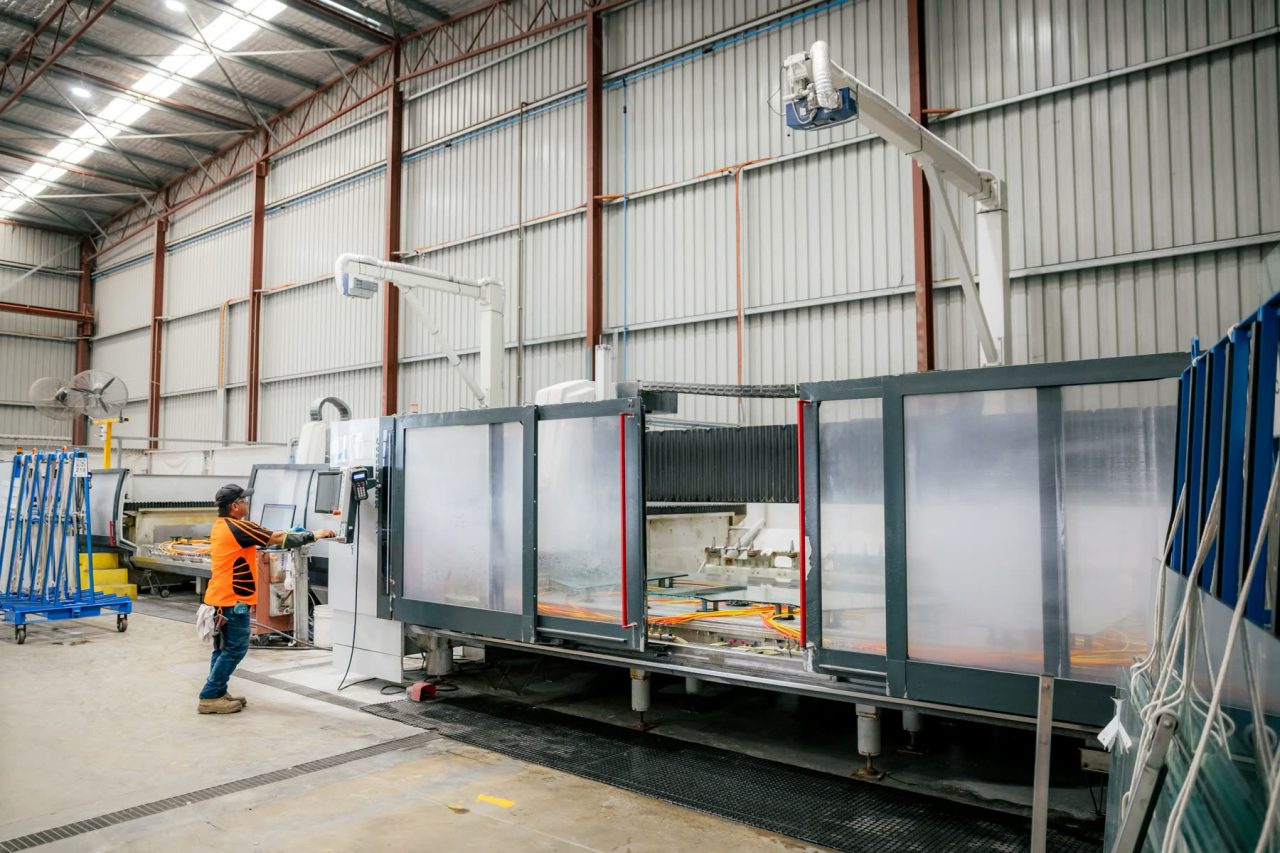 Operator running a CNC glass processing machine at Tough Glass.