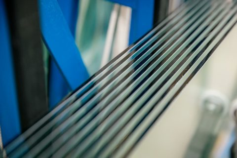 Close-up of stacked glass sheets showing different edge profiles and thicknesses.
