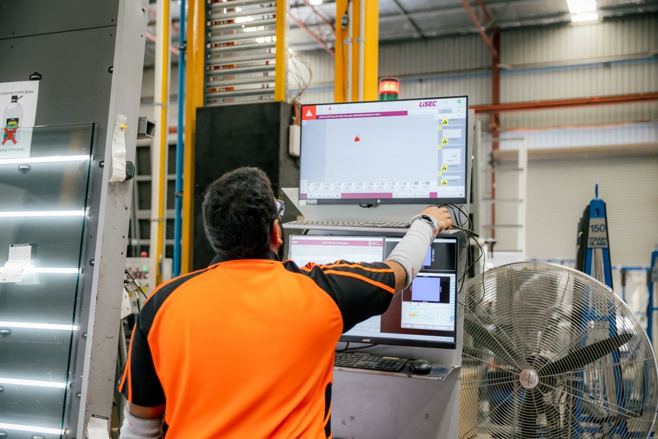 Tough Glass technician monitoring coated glass production at an inspection station.