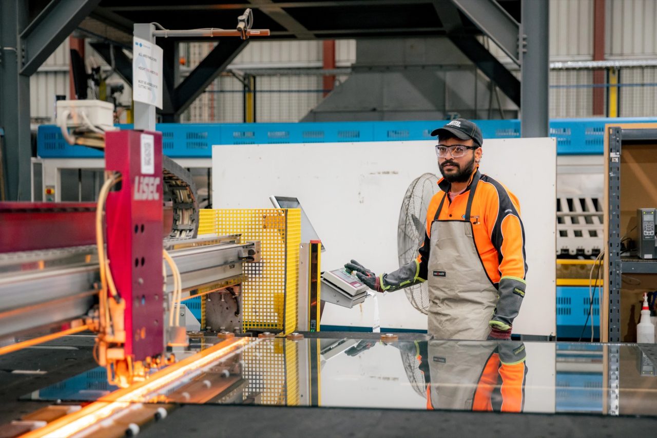 Tough Glass operator monitoring a heated glass processing line.