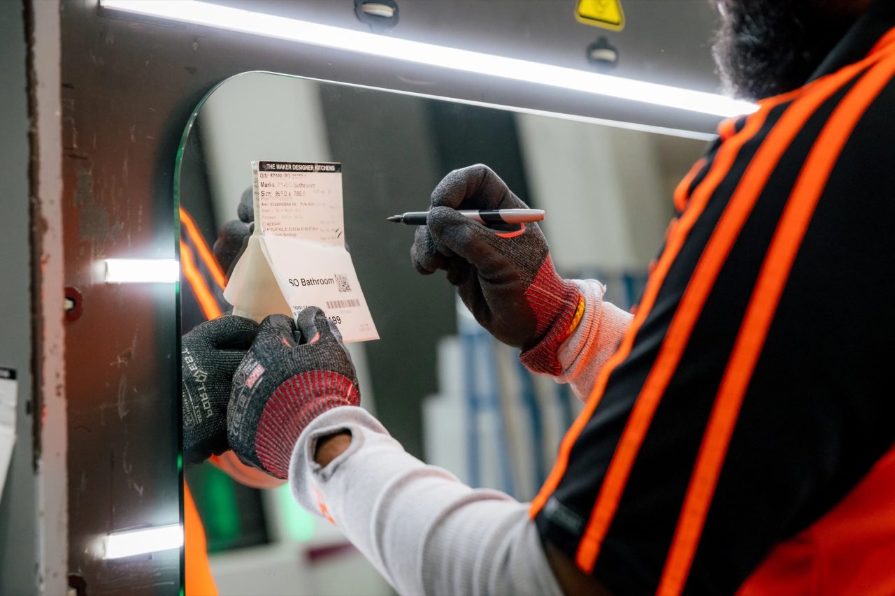 Tough Glass worker checking an inspection tag on a finished glass panel.