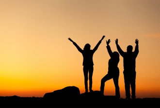 Silhouette of happy family with arms raised up at sunset