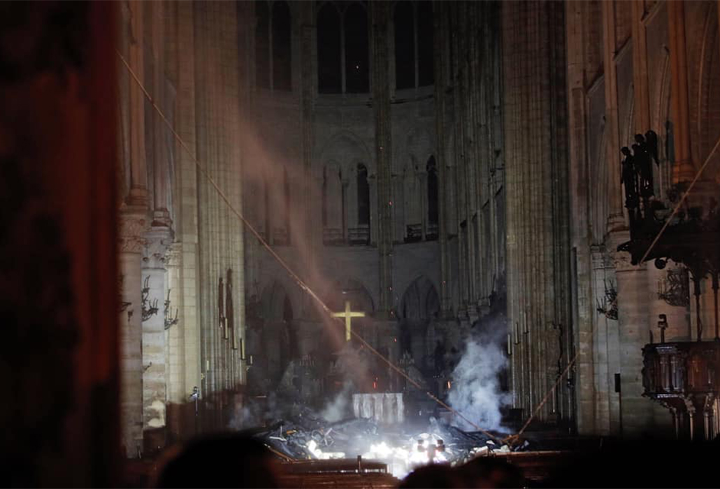 The Cross of Jesus, the Christ, illuminated among the ruins of Notre Dame Cathedral Paris, following the fire that nearly destroyed this shining icon at the heart of France and its people.