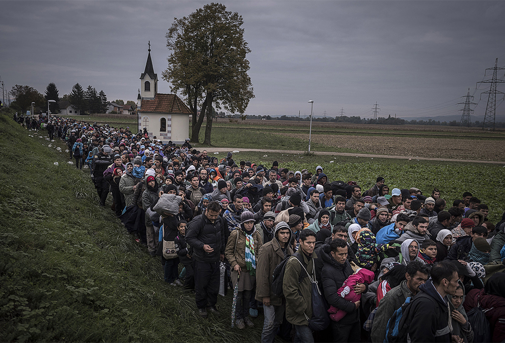 Migrants walk past the temple as they are escorted by Slovenian riot police to the registration camp outside Dobova, Slovenia, Thursday October, 22, 2015. (Photo Sergey Ponomarev for The New York Times) NYTCREDIT: Sergey Ponomarev for The New York Times