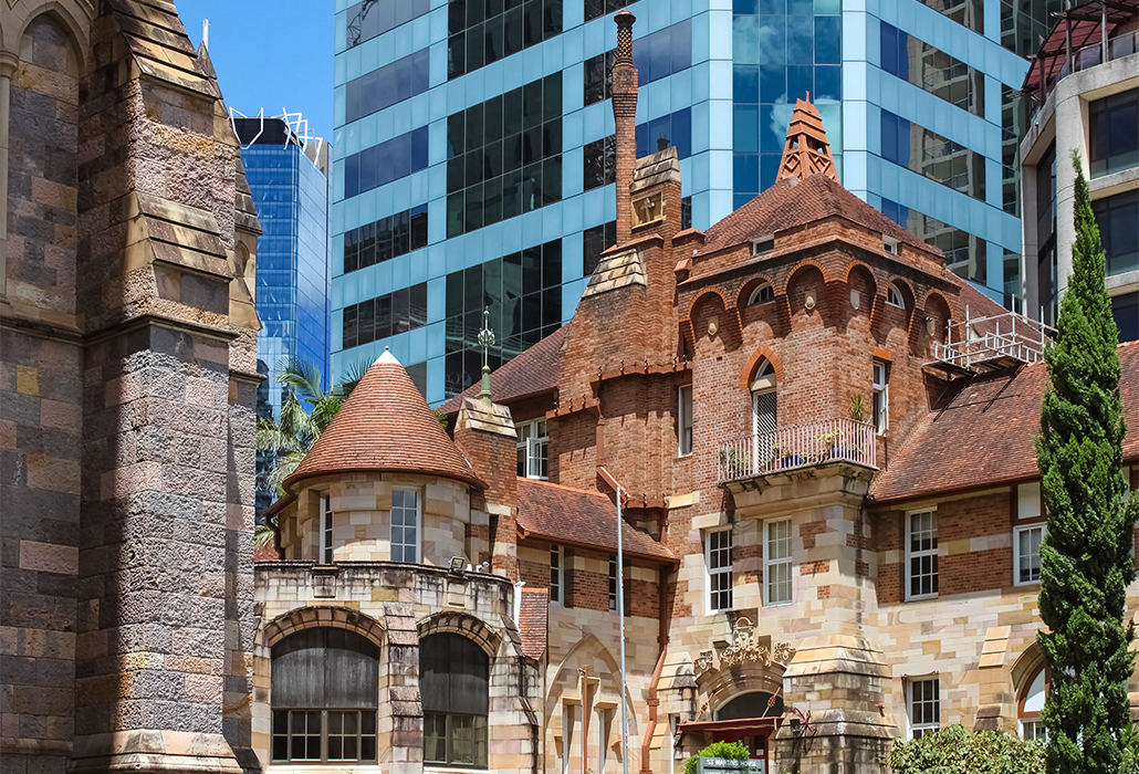 Juxapositon of both old and new buildings - St Martins House, a beautful and ornate former hospital and memorial for veterans stands against contemporary buildings in Brisbane, Australia and next to St John's Cathedral