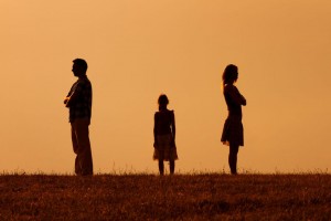 Silhouette of a angry husband and wife on each other with their daughter standing in the middle.